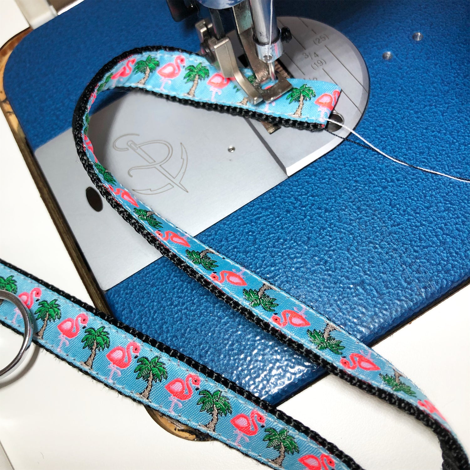 Marine webbing, flamingo and palm tree pattern jacquard ribbon being sewn on a sewing machine with industrial thread to make a dog collar.